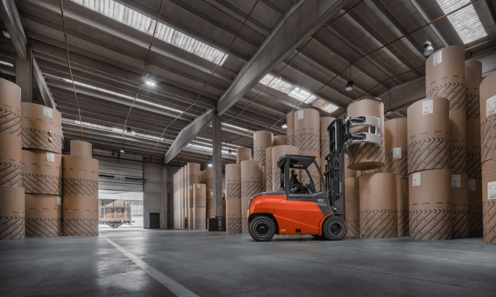 Toyota forklift  with clamp attachment stacking cylindrical drums in storage area