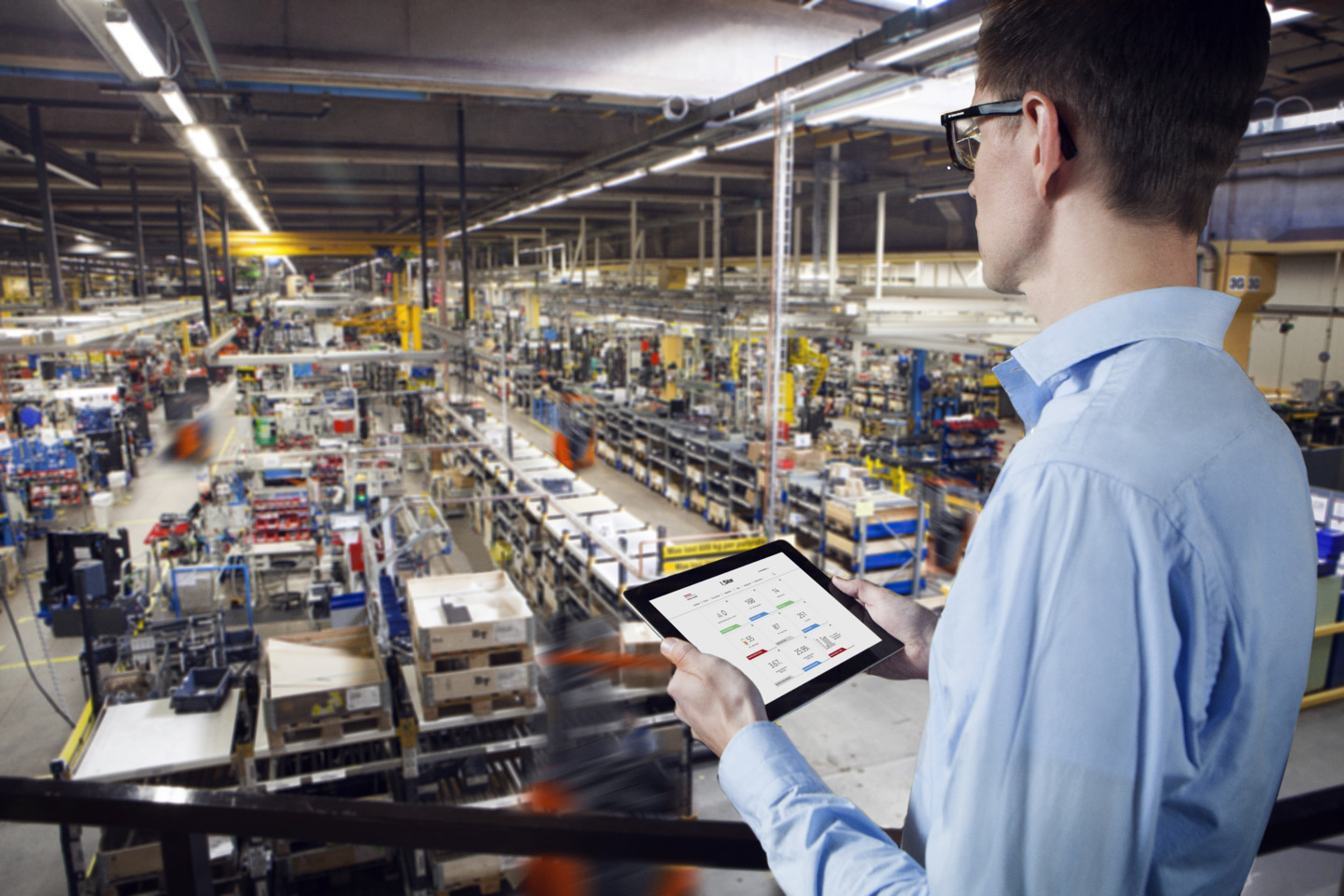 Employee surveying production environment from above and holds a tablet with the I_site application