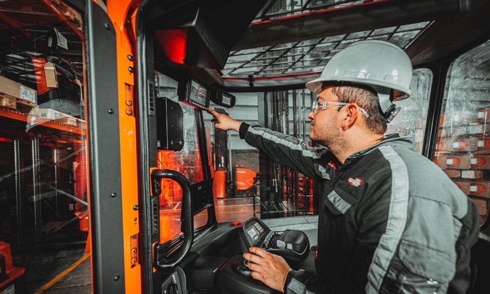 Application photograph of operator inside forklift checking back camera on screen. Attribution to Distoyota, Colombia. 