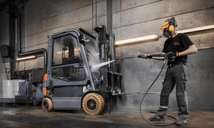 Employee washing used Toyota forklift with pressure washer