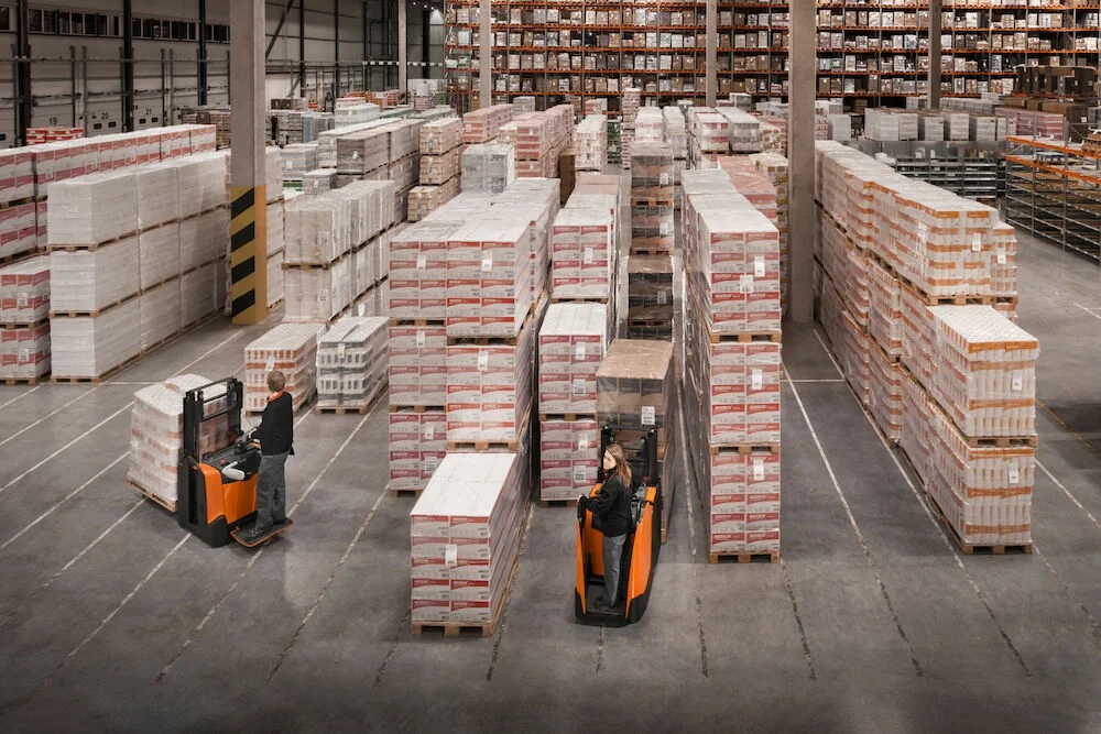 BT Staxio SPE200DN, electric stacker with double load handling and fixed side guards. Application photo in warehouse environment.