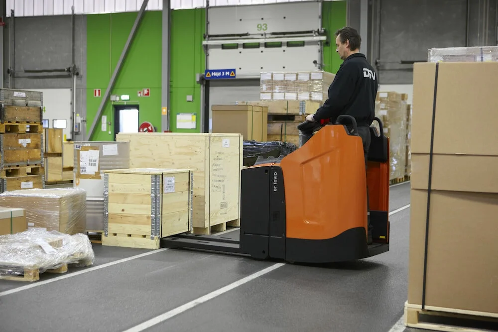BT Levio powered pallet truck, electric low-lifter with fixed side guards option. Application photo in a warehouse environment. 