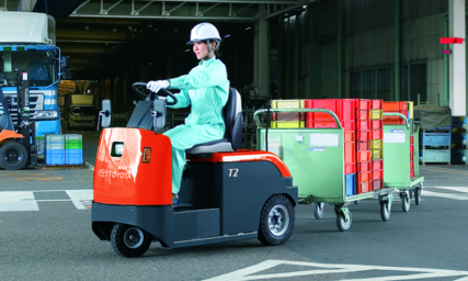 Toyota towing tractor 4CBT towing carriages on wheels outside under roof