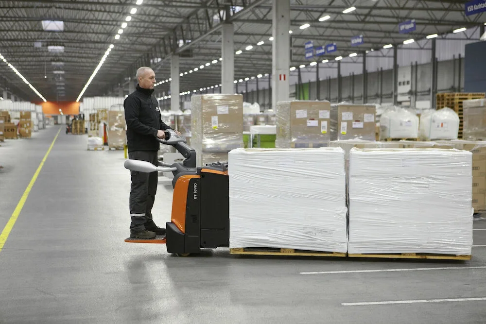 BT Levio powered pallet truck, electric low-lifter with long forks option. Application photo in a warehouse environment. 