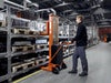 Toyota Lifter SHL080 hand pallet truck, electric stacker with forks raised. Application photo in a manufacturing environment. 