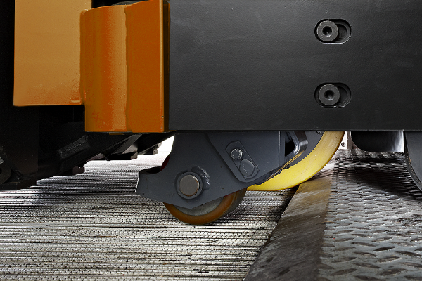 Close-up of forklift wheels driving on uneven surface.